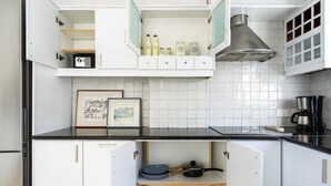 A kitchen with white cabinets, a black countertop, and a stainless steel range hood. - Oracle 2-BR Apt. & Balcony in Larnaca (Larnaca)