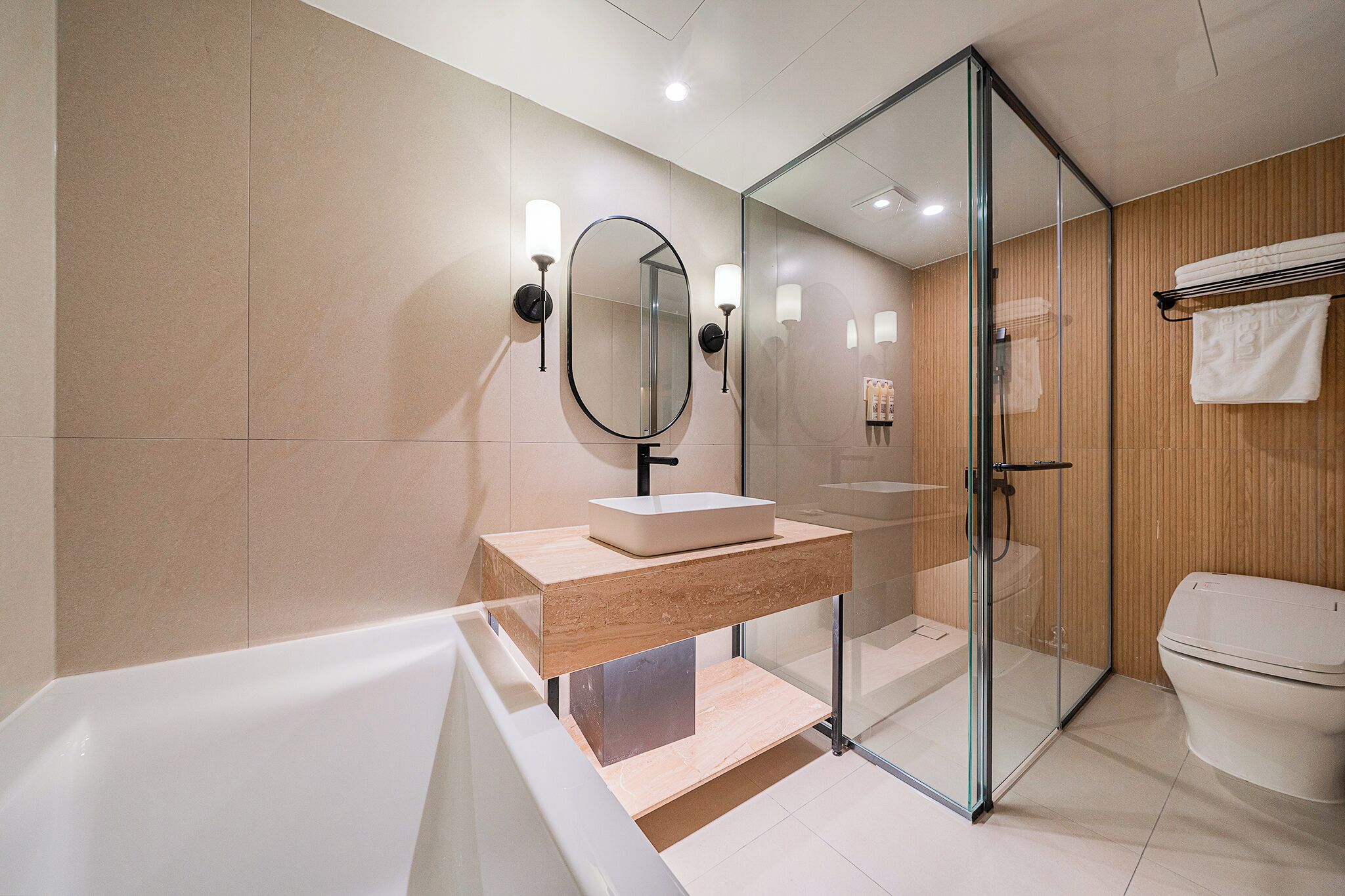 Une salle de bain moderne avec une douche à l’italienne en verre, un meuble-lavabo en bois et une baignoire blanche.