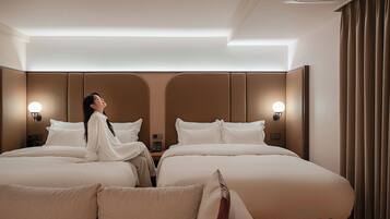 A hotel room with two beds, a headboard, bedside lamps, and a curtain.