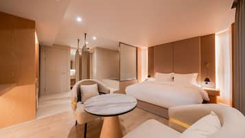 Ein modernes Hotelzimmer mit einem großen Bett, einem runden Tisch, zwei Sesseln und einem Spiegel.
