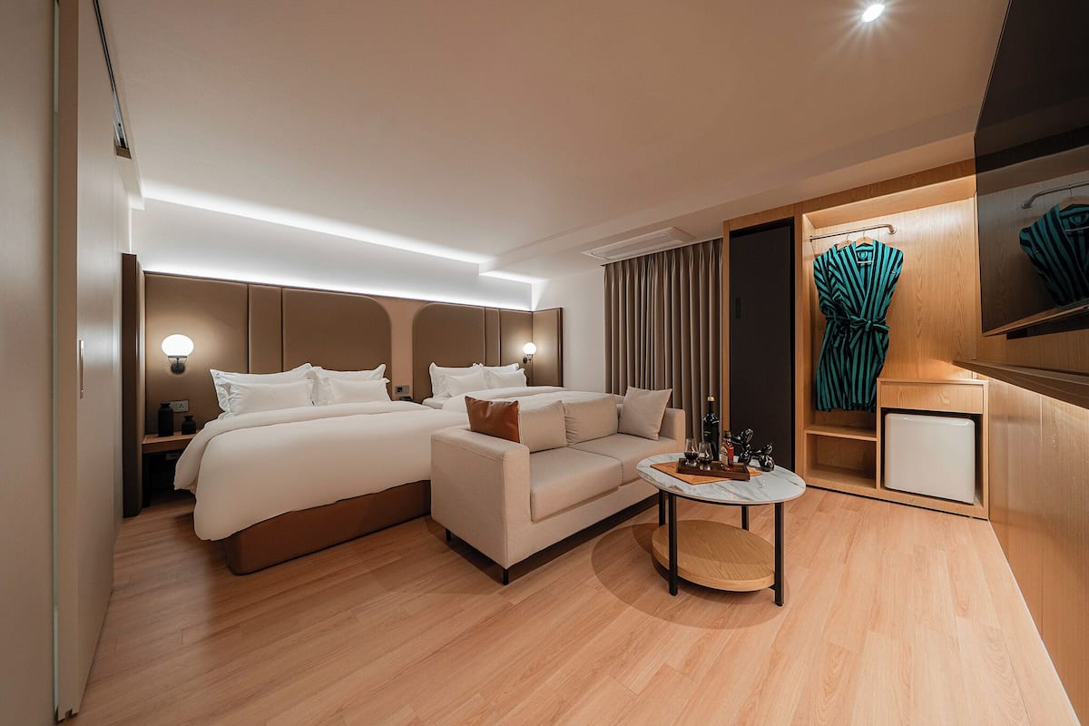 A modern hotel room with a bed, sofa, and a small table.