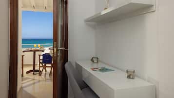 A room with a view of the beach, a white counter with a magazine, and a chair with a towel.