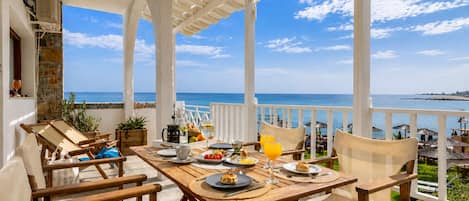A wooden table set with plates, glasses, and a pitcher, overlooking a coastal view.