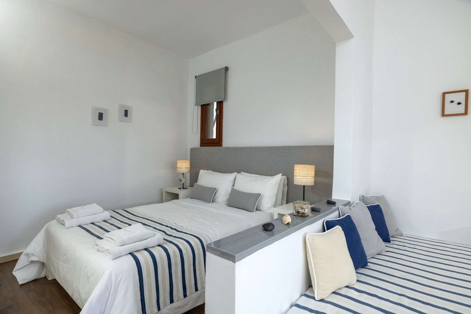 Une chambre d’hôtel comprenant un lit, des tables de chevet, des lampes et un petit coin salon avec des coussins.