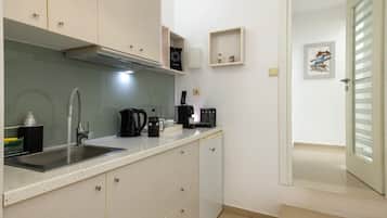 A compact kitchen with a sink, coffee maker, and cabinets.