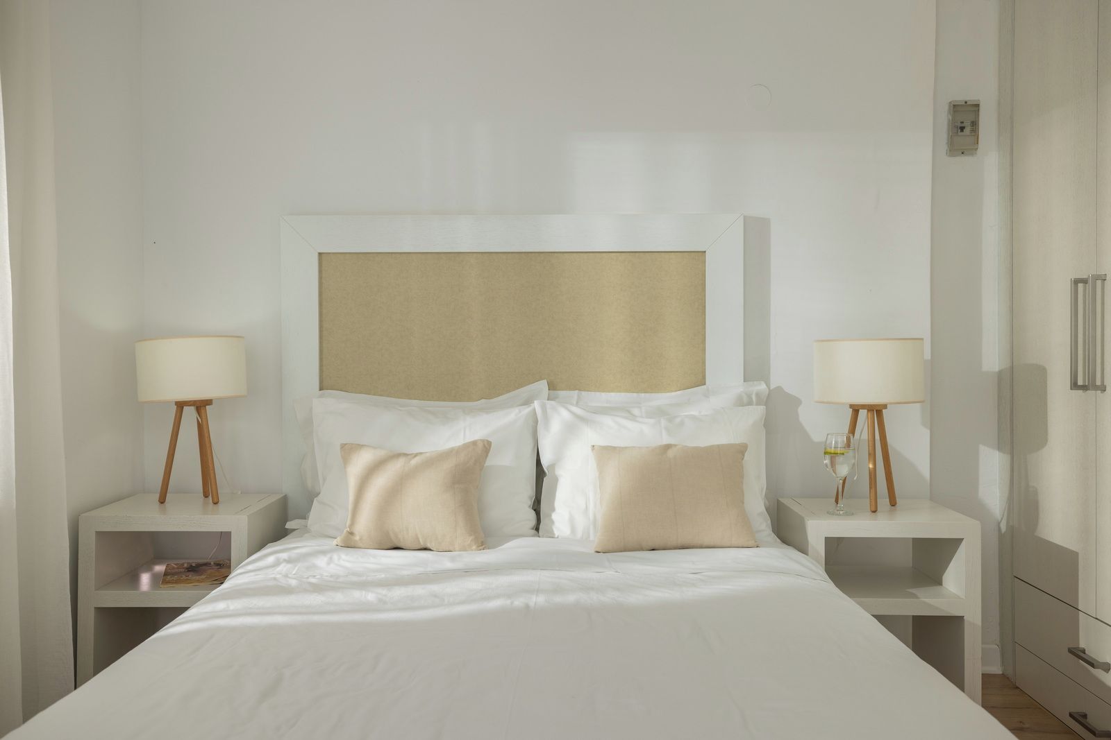 A hotel room with a large bed, two bedside tables, and a headboard.