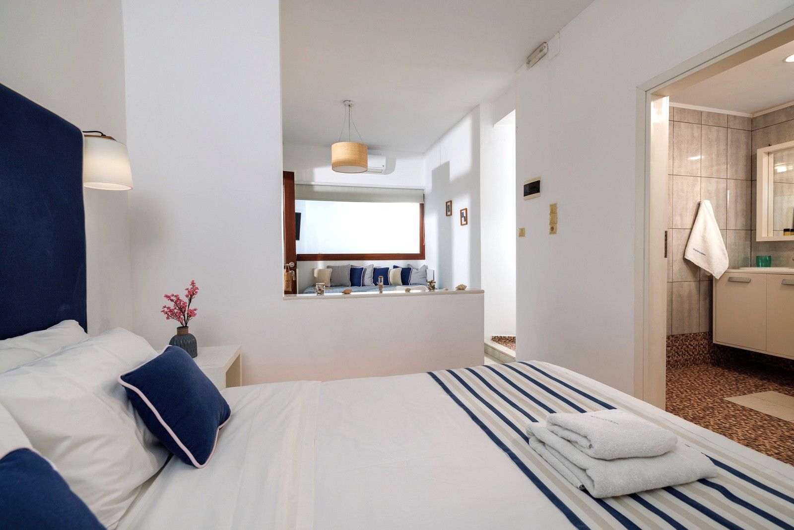 A hotel room with a large bed, a bedside table, a mirror, and a view of the bathroom.