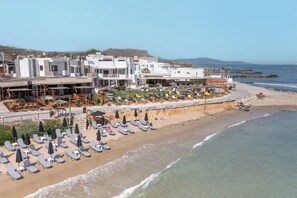 A coastal hotel with multiple floors, beachside lounge chairs, and umbrellas. - Golden Grain Beachfront Suites (Hersonissos)