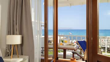 A room with a view of the sea, a table with breakfast items, and a chair with a towel.