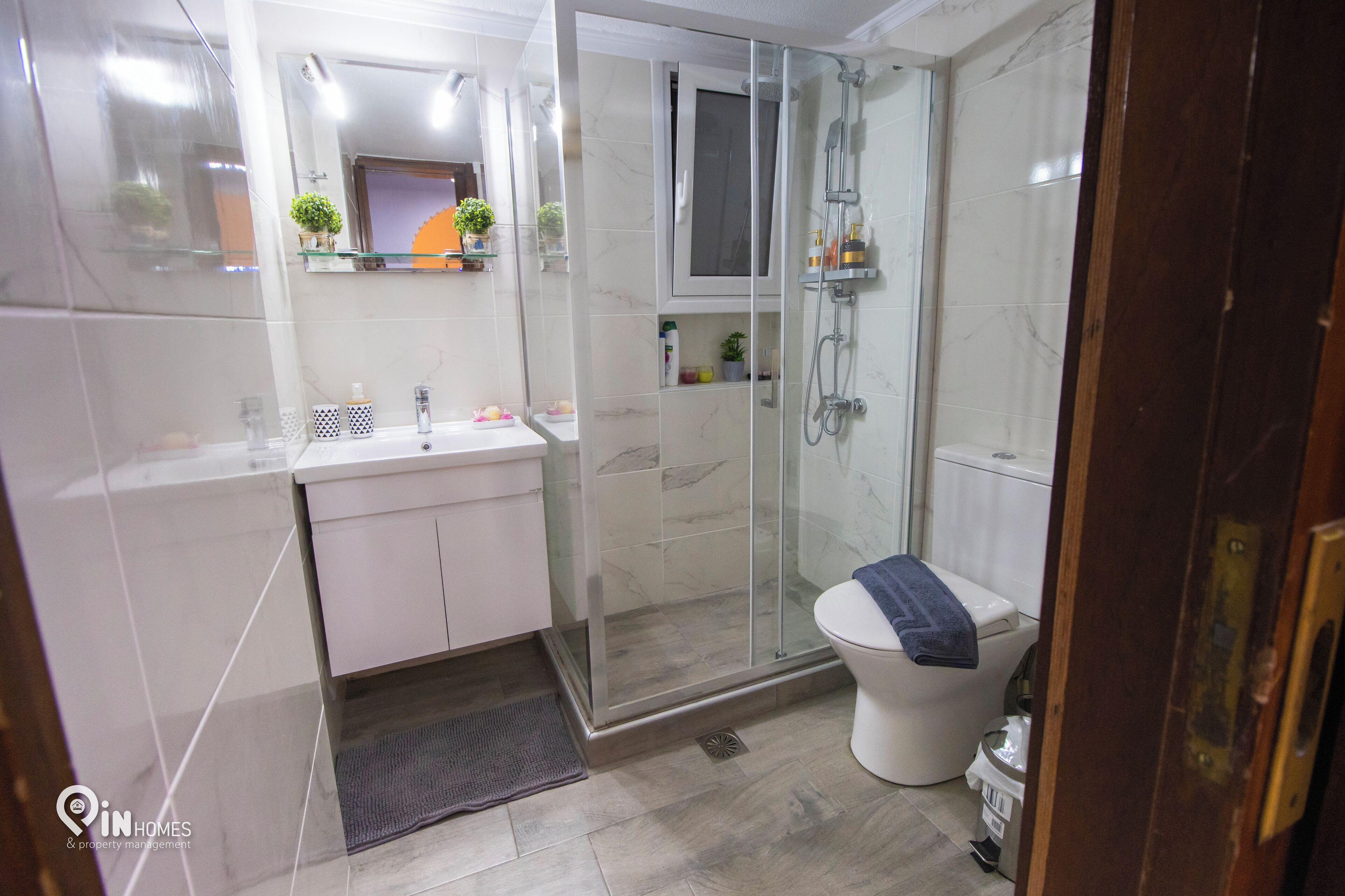 Un baño moderno con ducha de vidrio, lavamanos blanco y un inodoro.