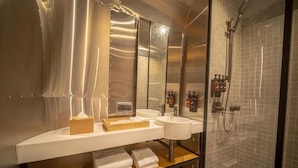 Une salle de bain moderne avec une douche à l’italienne en verre, un meuble-lavabo doté de deux vasques et un miroir au-dessus du meuble-lavabo.