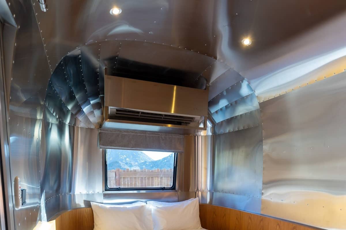 Een compacte, goed verlichte kamer met een enkel bed, een raam met uitzicht op de bergen en een ingebouwde airconditioning.