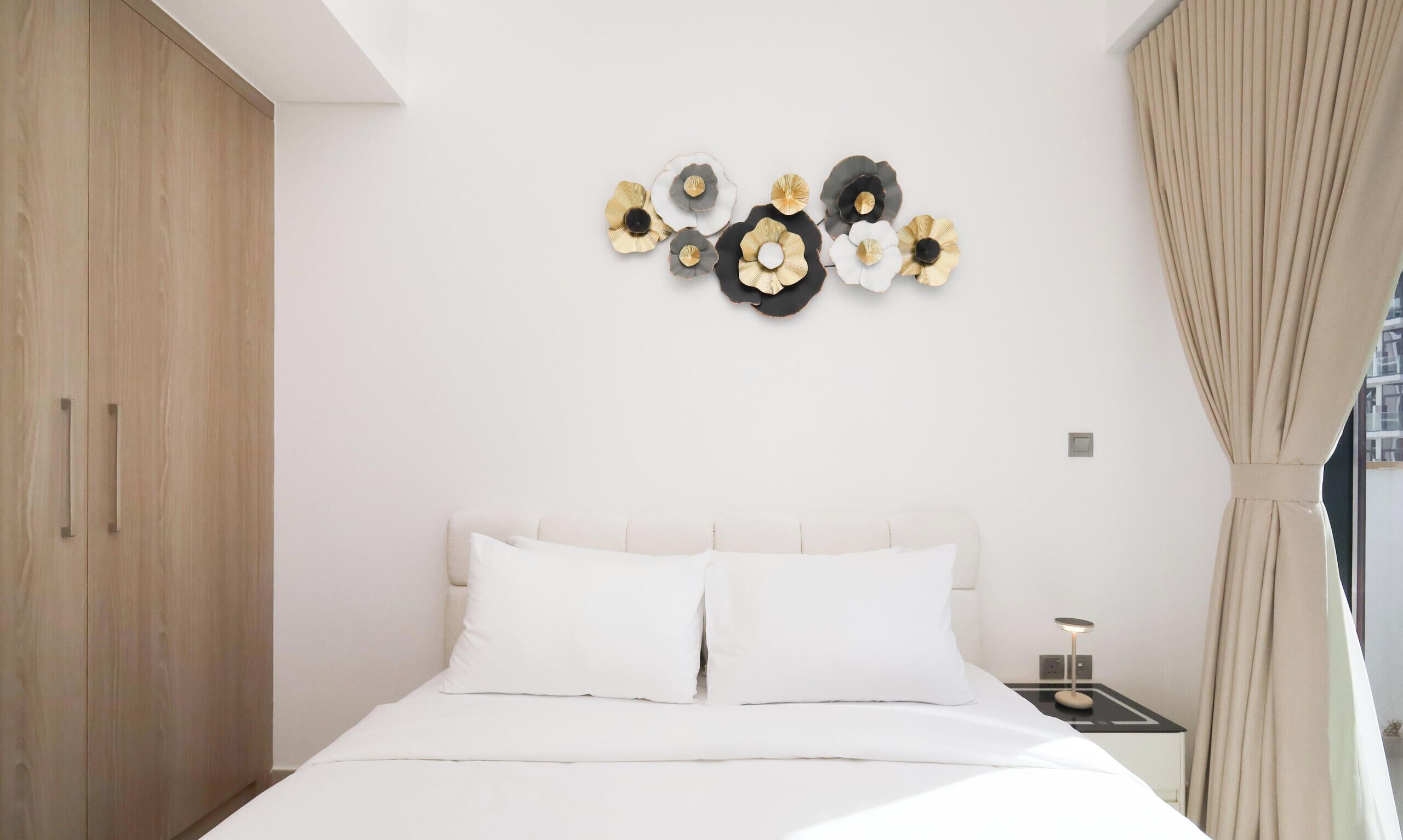 A modern bedroom with a bed, a nightstand, and a wall-mounted decorative piece.
