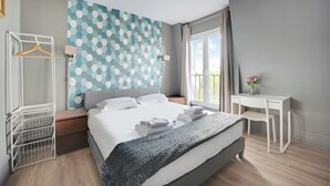 A modern hotel room with a large bed, a desk, and a view of the outdoors. - Studio Cosy - 2P - Canal Saint Martin (Paris)