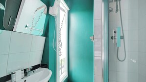 A bathroom with a white sink, a mirror, and a shower area. - Studio Cosy - 2P - Canal Saint Martin (Paris)