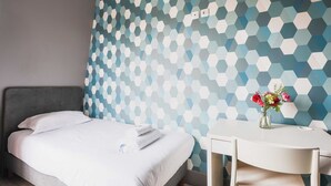 A hotel room with a bed, a desk, and a chair. There is a wall with a geometric pattern. - Charming studio - 1P- Canal Saint-Martin (Paris)