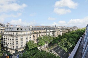 A row of historic European-style buildings with uniform facades and balconies, lined with trees and a clear sky. - Charming studio - 1P- Canal Saint-Martin (Paris)