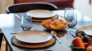 A dining table set with plates, glasses, and a basket of fruit.