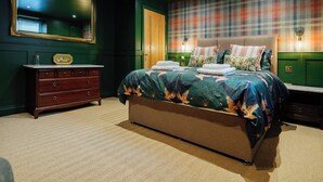 A bedroom with a large bed, a dresser, a mirror, and a plaid-patterned wall.