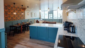 A modern kitchen with blue cabinetry, a marble countertop, and pendant lighting.