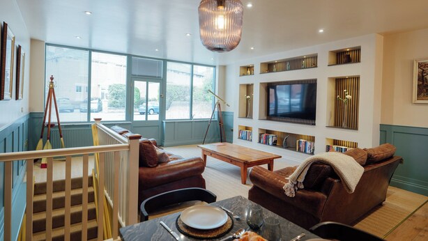 A spacious living room with a large TV, bookshelves, a wooden coffee table, and a comfortable seating area.