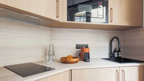 Et moderne køkken med en Bosch mikrobølgeovn, kaffemaskine og vask.