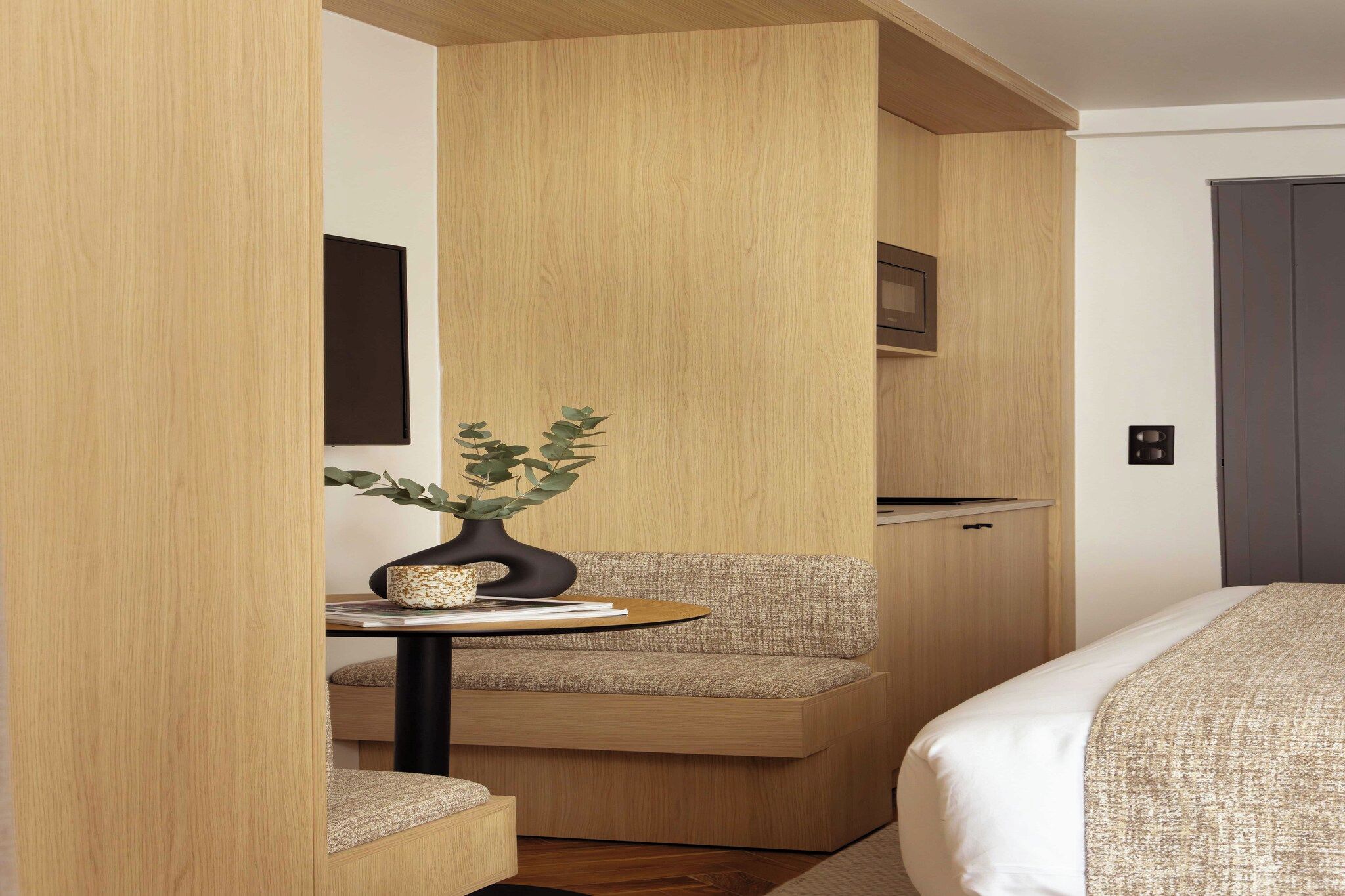 Habitación de hotel compacta con kitchenette, una pequeña zona de estar y una cama.