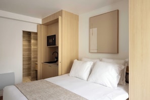 A modern hotel room with a bed, a built-in desk, a microwave, and a large mirror. - Cocooning studio Jardin de Luxembourg/Panthéon (Paris)
