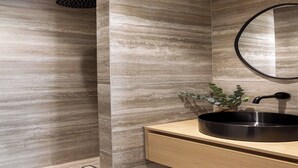 Ein modernes Badezimmer mit einem großen Waschbecken, einem Spiegel und einer Dusche.