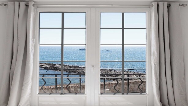 Eine Doppeltür mit Blick auf das Meer und die felsige Küste.
