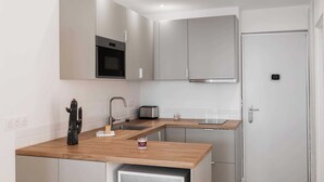 Eine moderne Küche mit einer Holzausziehtheke, Edelstahlgeräten und einer weißen Tür.