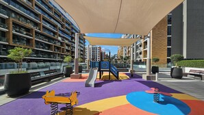 A playground with colorful play equipment and a covered seating area. - Stylish Riviera Studio Near Downtown (Dubai)