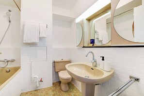 A bathroom with a bathtub, toilet, sink, and a large mirror. - Charming studio - 2P - balcony - Saint Honore (Paris)
