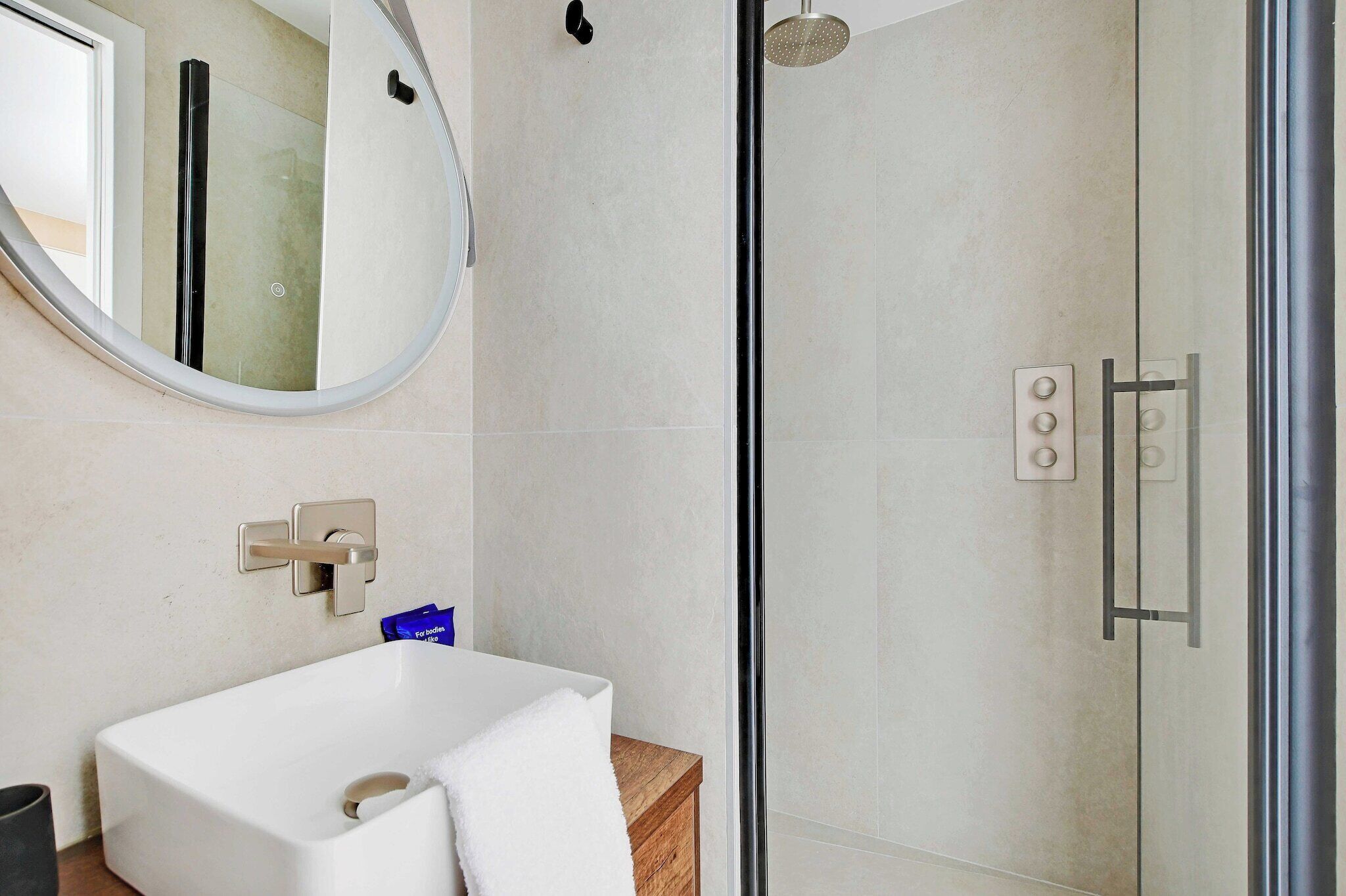 A modern bathroom with a glass-enclosed shower, a white sink, and a mirror.