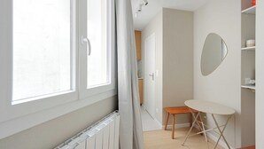 A bright room with a radiator, a window, a mirror, and a small table. - Cosy Studio 2P - Paris 01/Musée du Louvre (Paris)