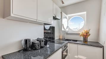 A modern kitchen with a black granite countertop, stainless steel appliances, and a window with a view of a tower.