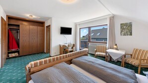 A hotel room with two beds, a TV, a desk, a chair, and a window with a view.