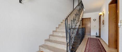 Eine Treppe mit Handlauf, Fußmatte und einem gemusterten Teppich.