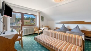 A hotel room with a bed, a desk, a chair, a TV, and a window with a view.