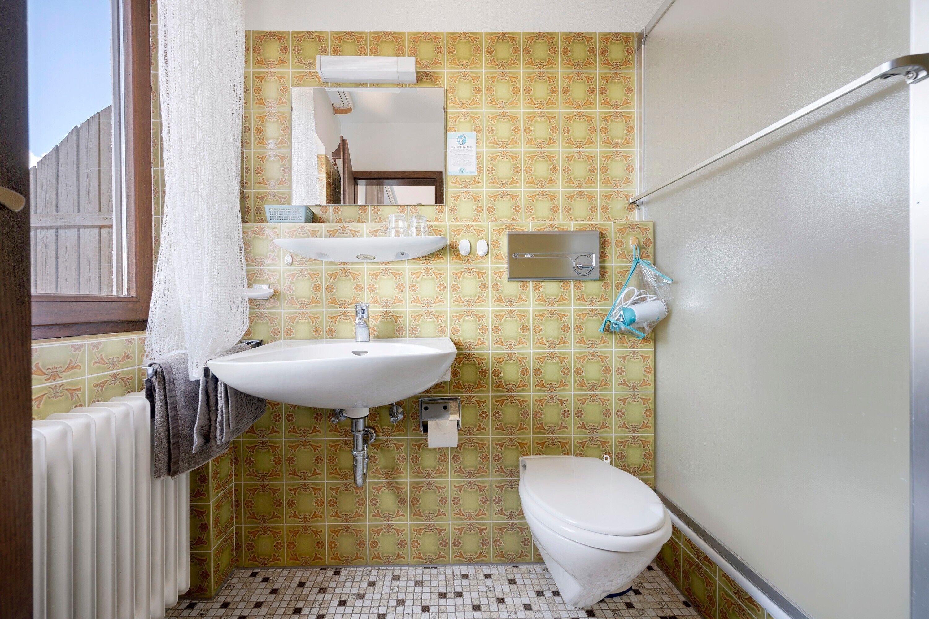 Un baño con lavabo, inodoro y ventana con persiana de madera.