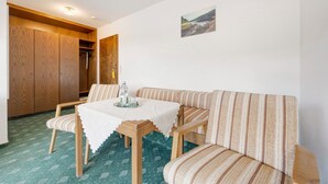 Une pièce comprenant une armoire en bois, un canapé, une table avec un plateau et un tableau accroché au mur.