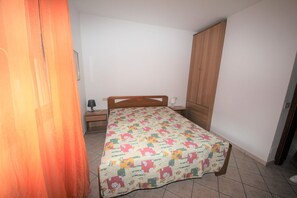 Une chambre à coucher avec un lit, une table de chevet, une armoire et une porte.
