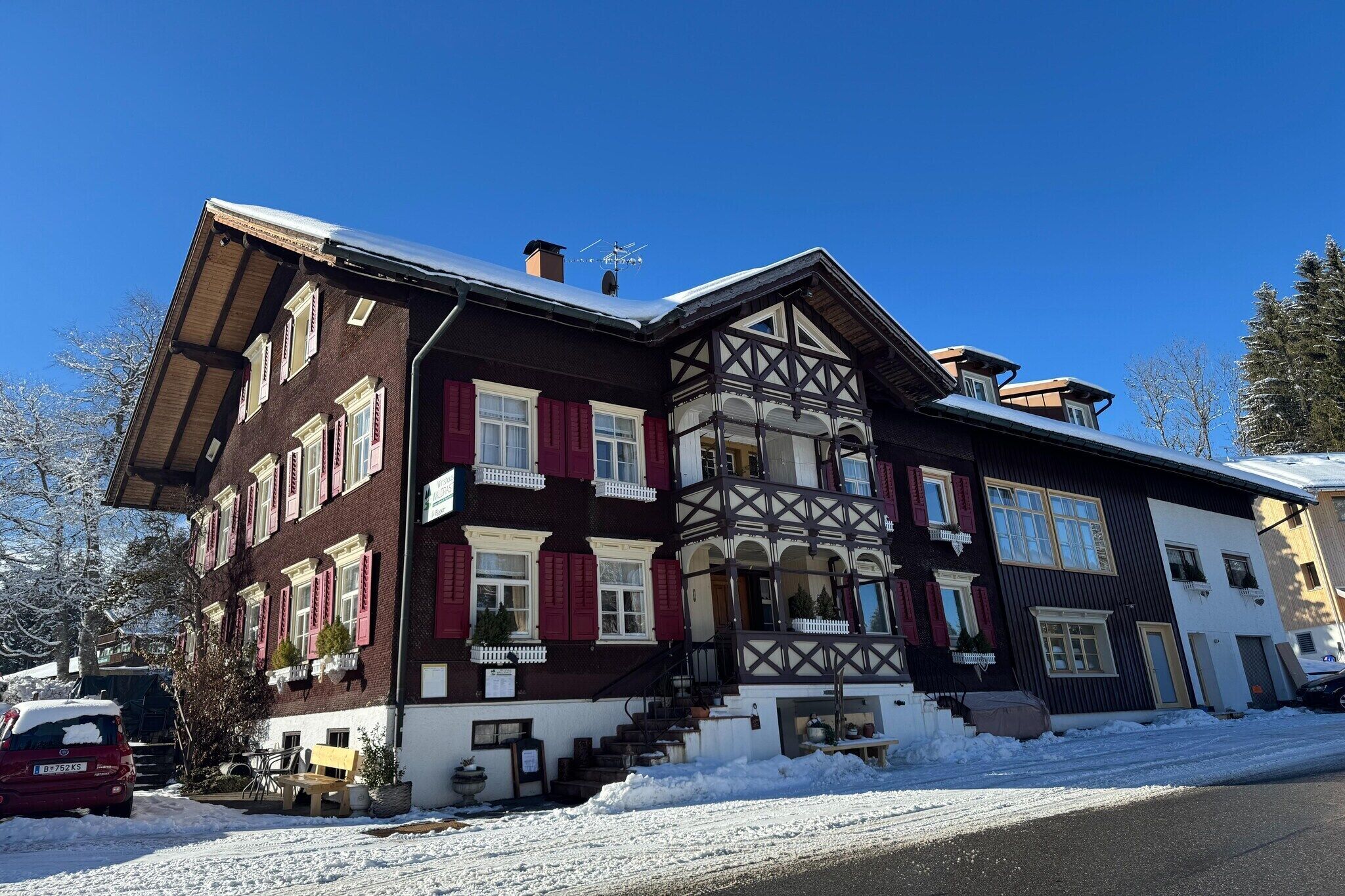 Ein mehrstöckiges Gebäude im traditionellen Baustil, mit einem Balkon und einer Treppe, die zum Eingang führt.
