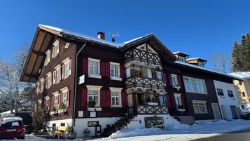 Ein mehrstöckiges Gebäude im traditionellen Baustil, mit einem Balkon und einer Treppe, die zum Eingang führt.