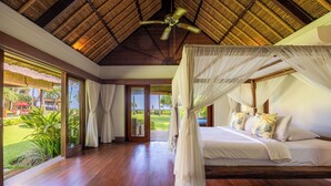 A bedroom with a canopy bed, wooden flooring, and a view of the outdoors. - Villa Maridadi Cemagi (Cemagi)