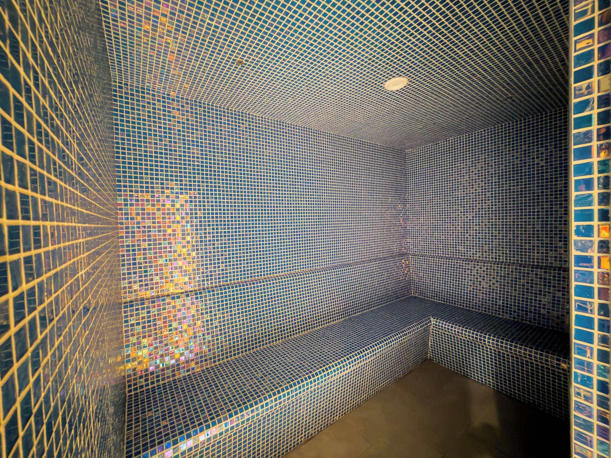 A room with a patterned tiled wall and a bench.