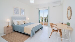 Un dormitorio con cama, mesita de noche, lámpara y vistas al exterior a través de una puerta corrediza.