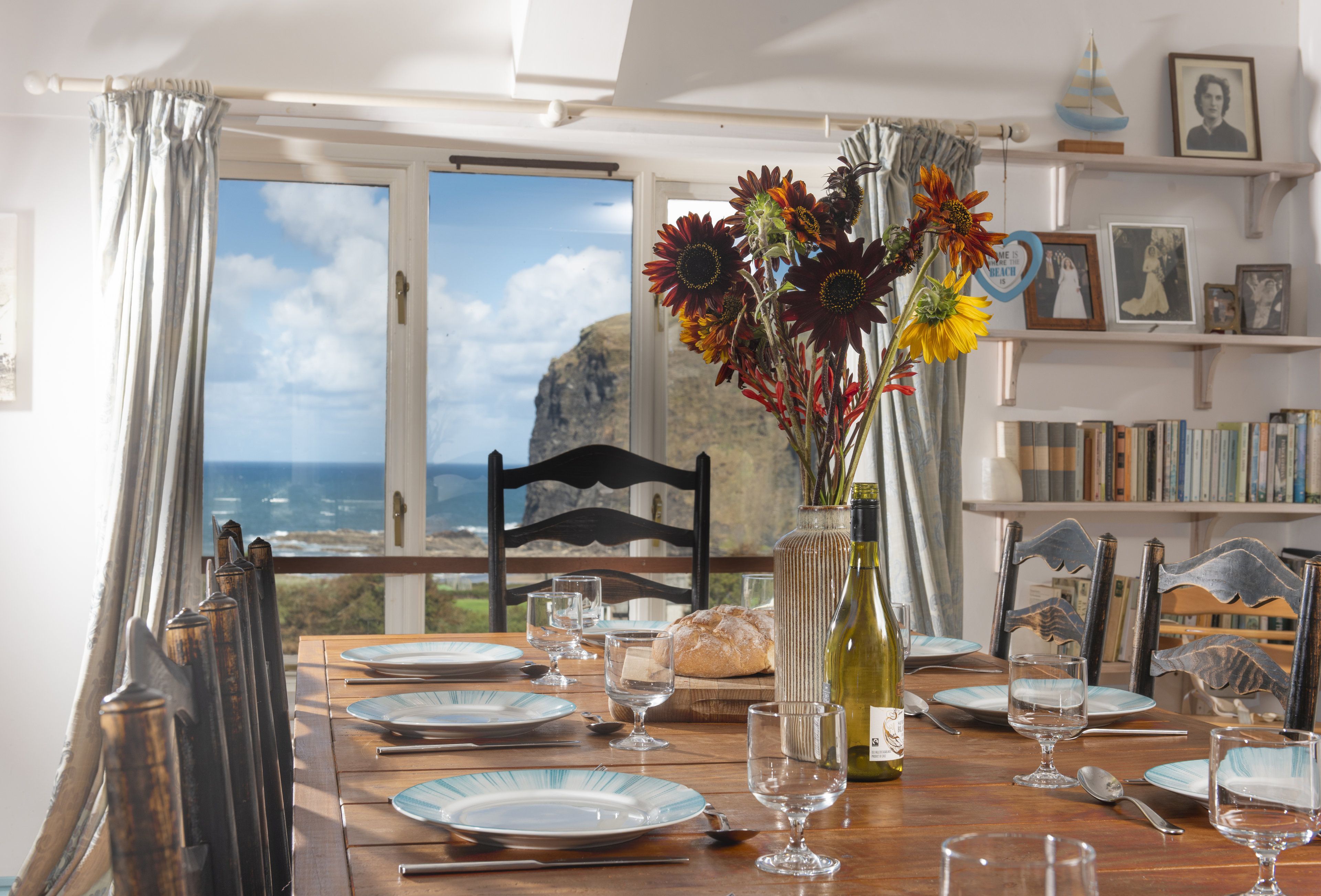 Une table à manger dressée avec des assiettes, des verres et un vase de fleurs, offrant une vue panoramique.