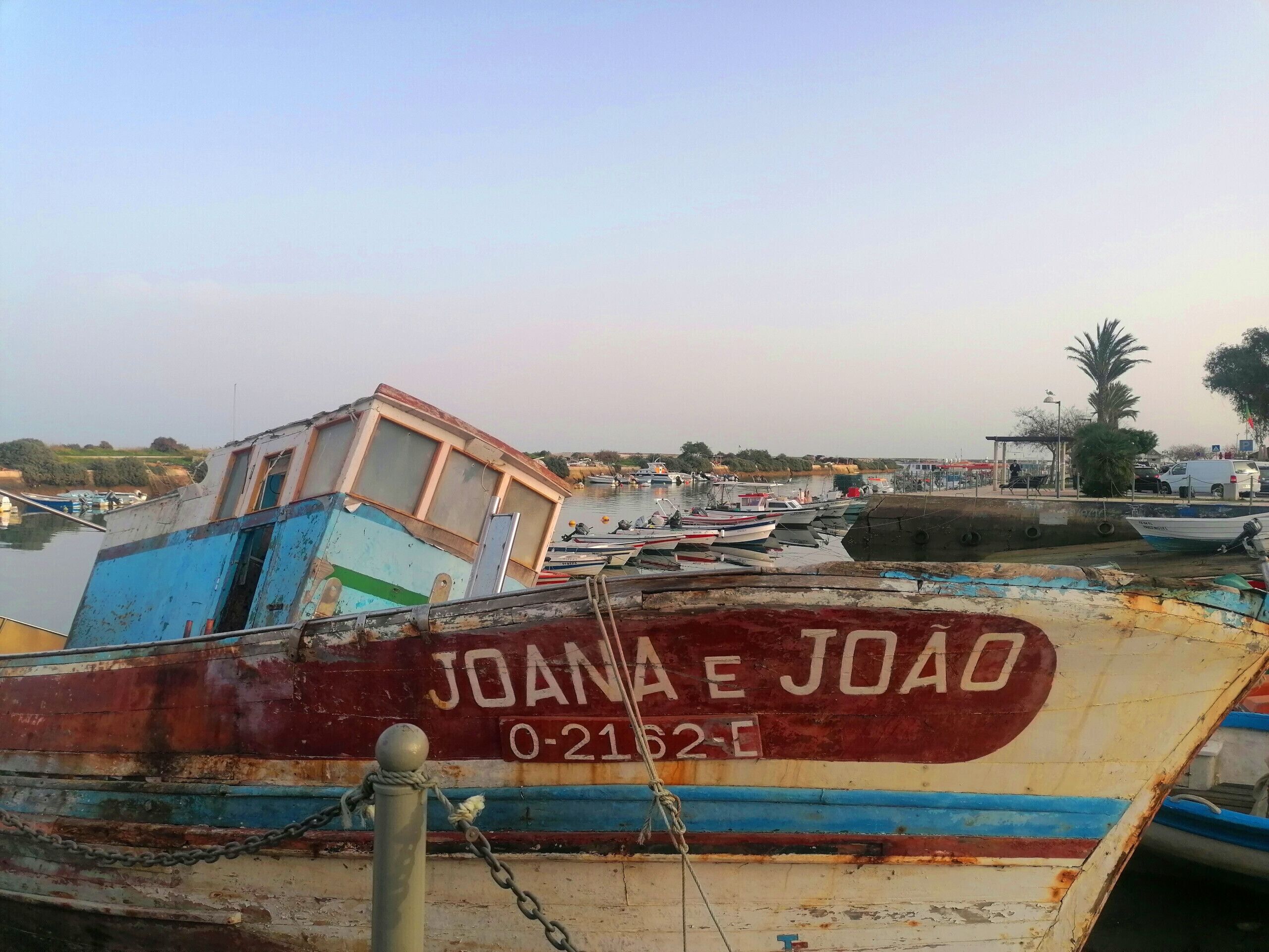A marina with several boats, including one with "JOANA E JOAO" and a registration number.
