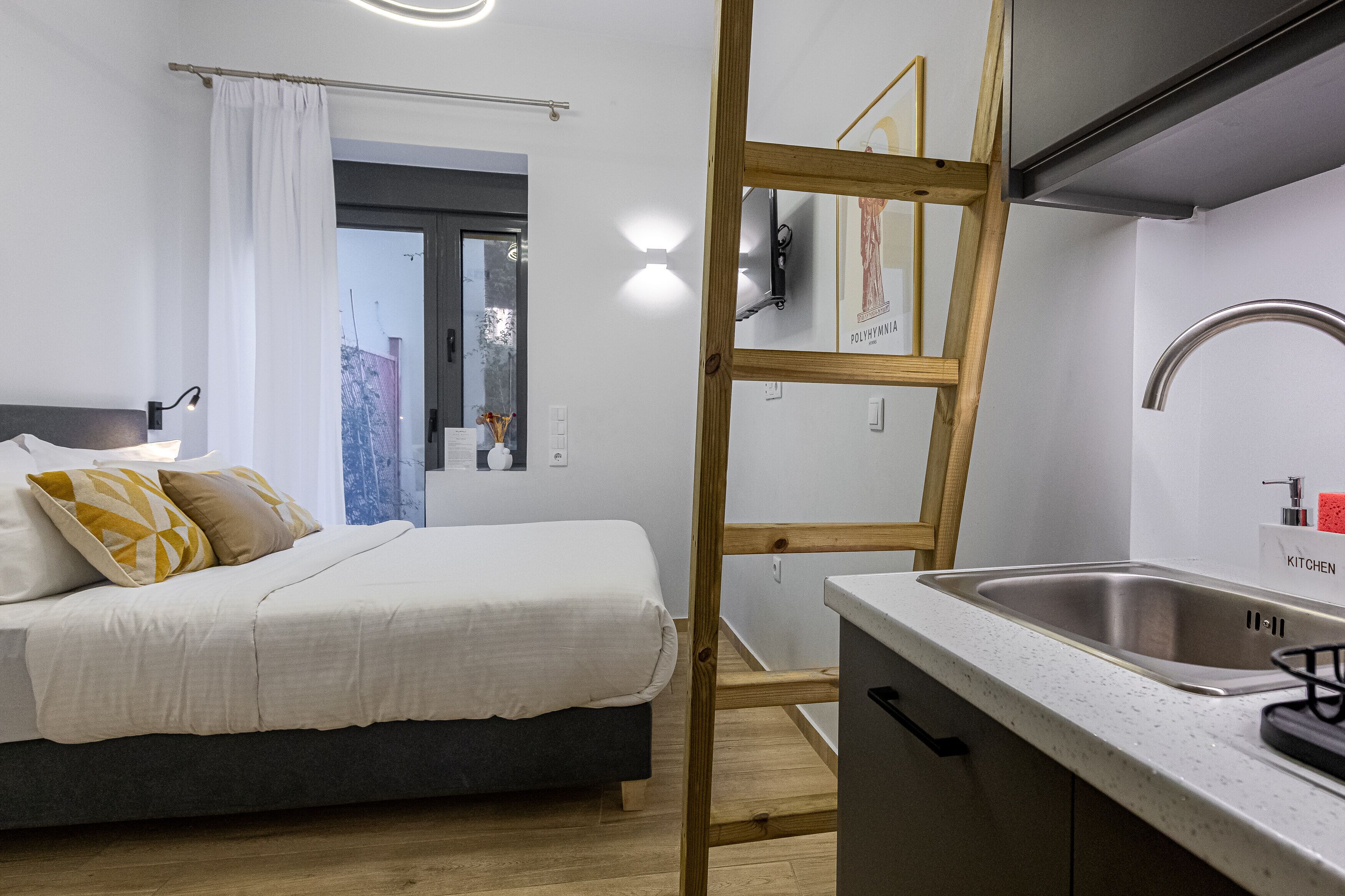 A bedroom with a bed, bedside table, and a view of the outside.